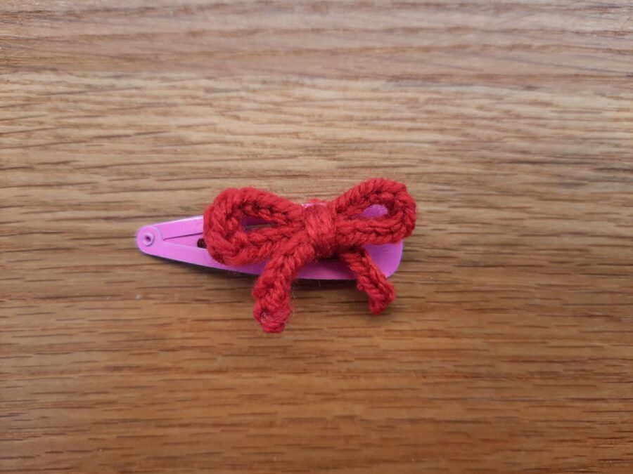 A hair clip decorated with a bow, made using the lucet