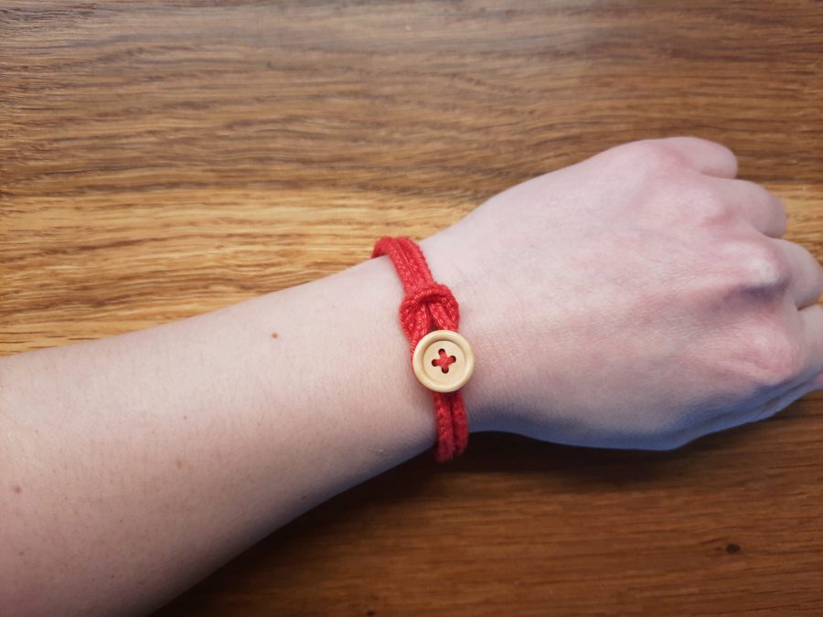 Red lucetted bracelet with wooden buton and knot-like closure