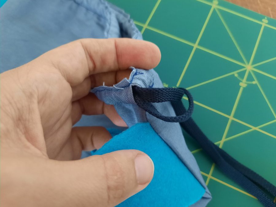 Threading two blue shoelaces as the bag's closing