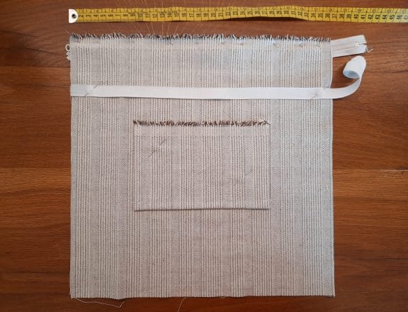Preparing the pocket for my embroidery project travel bag: pin the pocket in place and measure where you want your elastic band