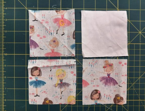 Sewing a corner bookmark: cutting three squares of fabric, each 12 cm (4 in) wide.