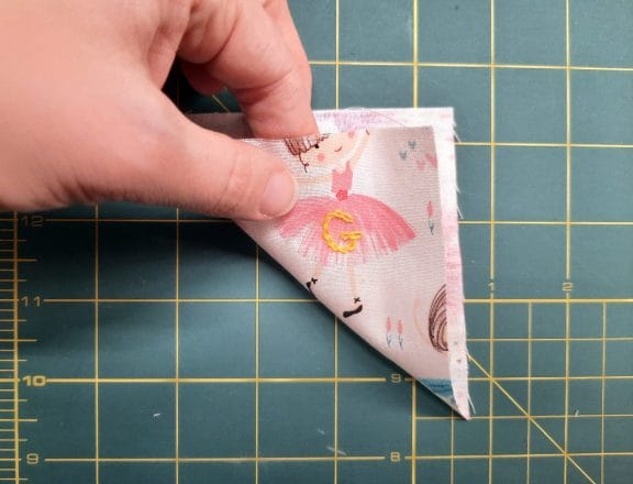 Sewing a corner bookmark: fold one of your squares diagonally, wrong sides together, to form a triangle.
