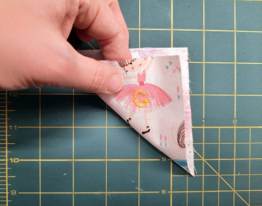 Sewing a corner bookmark: fold one of your squares diagonally, wrong sides together, to form a triangle.