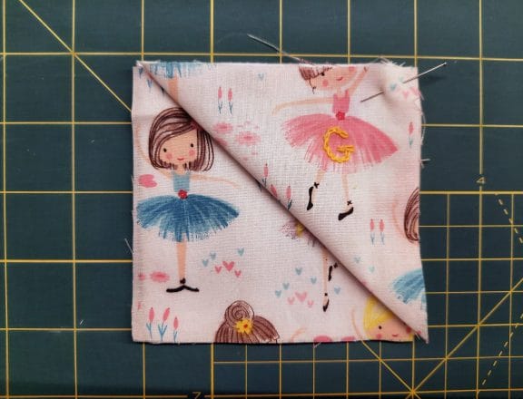 Sewing a corner bookmark: lay one fabric square right side up, then place the folded triangle on top, aligning its raw edges with the top left of the square below.