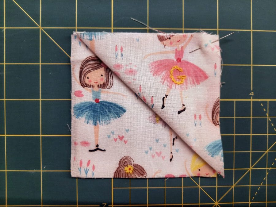 Sewing a corner bookmark: lay one fabric square right side up, then place the folded triangle on top, aligning its raw edges with the top left of the square below.