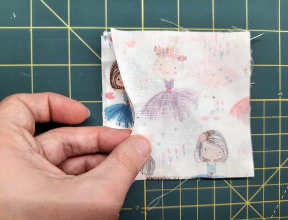 Sewing a corner bookmark: add the third square on top, this time right side down, creating a sandwich with the triangle in the middle.