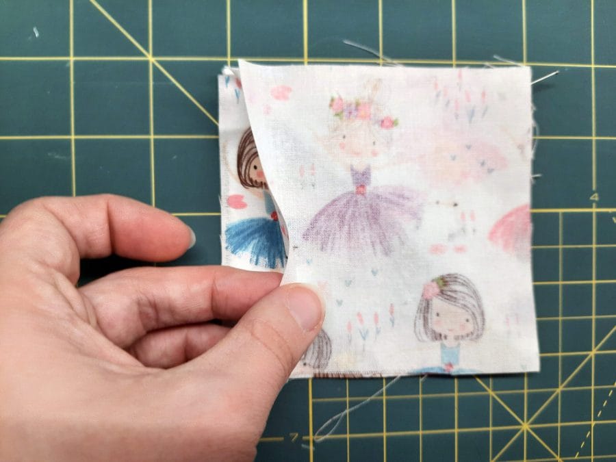 Sewing a corner bookmark: add the third square on top, this time right side down, creating a sandwich with the triangle in the middle.