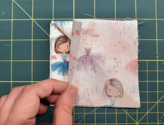 Sewing a corner bookmark: add the third square on top, this time right side down, creating a sandwich with the triangle in the middle.