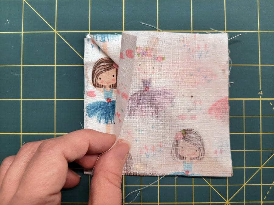 Sewing a corner bookmark: add the third square on top, this time right side down, creating a sandwich with the triangle in the middle.