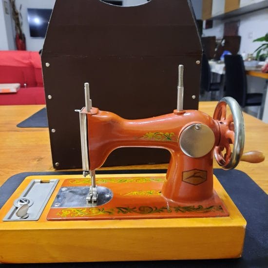 The Orsha toy sewing machine as it arrived home, with its original cardboard box. Notice how the base is mounted the other way around: it's on the left next to the needle plate, instead that on the right under the hand crank