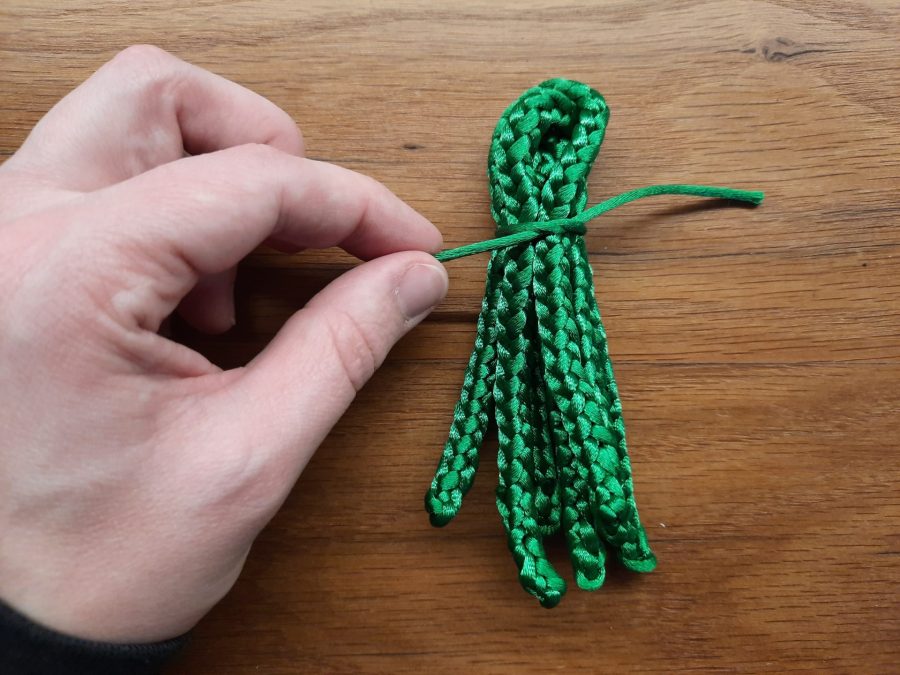 Making the octopus toy with the lucet: at the point where you want the head to finish and the tentacles to begin, wrap the bundle with yarn and secure