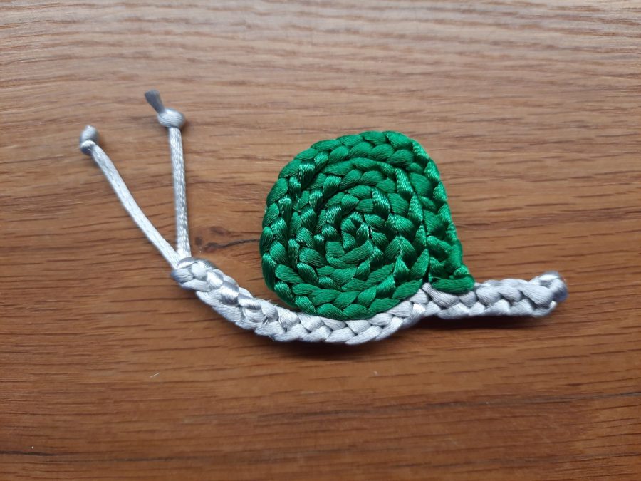 Making the snail toy with the lucet: sew together body and shell to assemble and finish