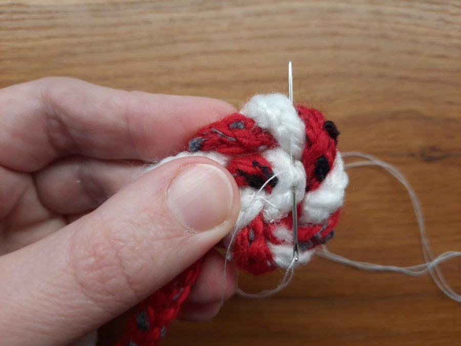 How to make a toy lollipop with the lucet: as you twist the cords, sew them in place in a spiral